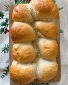 a loaf of bread sitting on top of a wooden cutting board next to pine branches