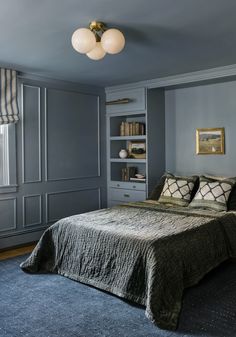 a bedroom with gray walls and blue carpeted flooring, built in bookshelves