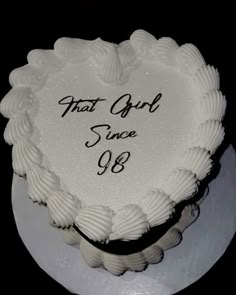 a white heart shaped cake with the words that girl since 98 on it's side