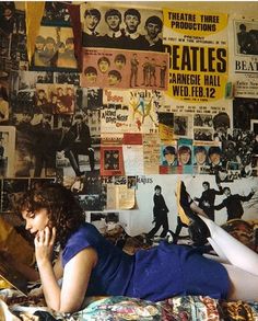 a woman laying on top of a bed covered in posters