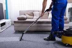 a man in blue overalls using a vacuum cleaner