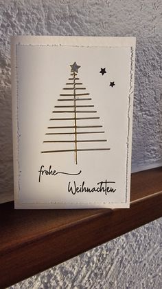 a card with a christmas tree on it sitting on a shelf next to a vase