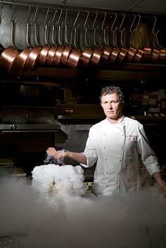 a chef standing in front of some steam coming out of his hands and cooking food