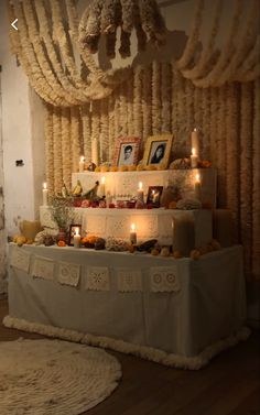 a table with candles and pictures on it in front of a wall hanging from the ceiling