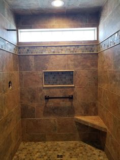 a walk in shower sitting under a window next to a tiled floor and counter top