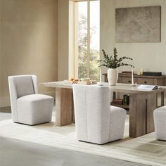 a dining room table with four chairs and a vase on the table next to it