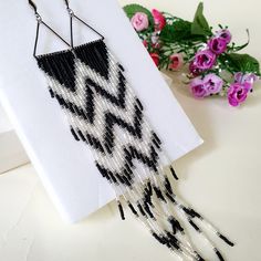 a pair of black and white beaded earrings sitting on top of a piece of paper