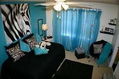 a bedroom decorated in zebra print and turquoise accents with black bedding, blue drapes, white curtains, and a stuffed animal