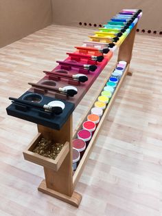 a table with many different colors of paint on it in a room filled with wooden floors