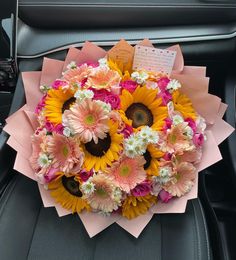 a bouquet of sunflowers and daisies in the back seat of a car