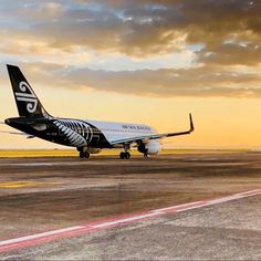 an air new zealand plane on the runway at sunset or dawn with clouds in the background