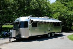 a silver trailer parked in front of some trees