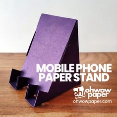 a purple paper phone stand sitting on top of a wooden table next to a white wall