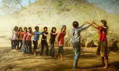 a group of young people standing on top of a dirt road next to a forest