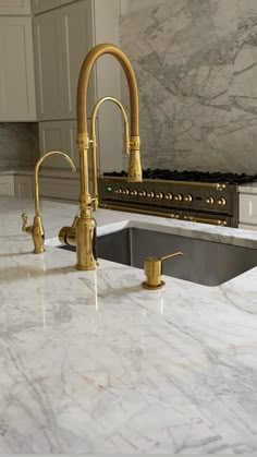 a kitchen with marble counter tops and gold faucets in the middle of it