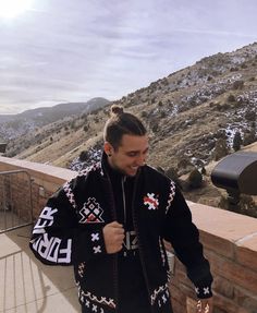 a man in a black jacket is standing on a ledge