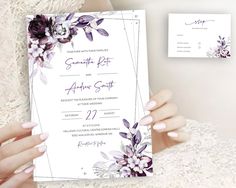 a woman holding up a wedding card with purple flowers on the front and back side