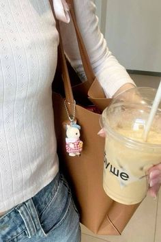 a woman holding a brown bag and a cup with a straw in it's hand