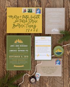 the wedding stationery is laid out on a wooden table with pine branches and other items