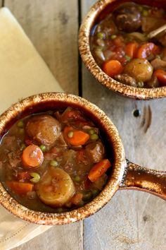 two bowls filled with stew on top of a wooden table