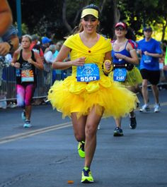 a woman in a yellow tutu running down the street with other runners behind her