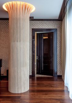 a tall column in the middle of a room with wood flooring and wallpaper