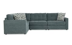 a gray sectional couch with pillows on the back and armrests, sitting in front of a white background