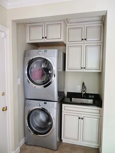 a washer and dryer in a kitchen with white cabinets on either side of the door