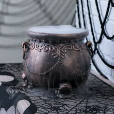 an ornately decorated metal container sits on a lace covered tablecloth in front of a black and white wall