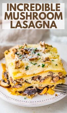 a white plate topped with lasagna covered in mushrooms and cheese, next to a fork