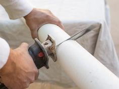 a man is using a pair of scissors to cut the pipe with a white handle