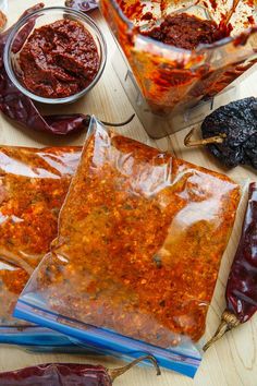 several bags of chili paste sitting on top of a wooden table next to some peppers