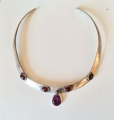 "This Sterling silver collar is 16\"long and about 1/2\"wide.The whole thing has been hammered and brushed on the inside.There are 4 large red garnet cabachons  and they are bezel set in Sterling and a big pear shaped ,at least 4 carat amethyst ,with a tiny blue swarovski crystal on the tip.The amethyst is not perfect and has flaws, yet still, beautiful! This heavy piece is comfortable to wear.  Shipping and giftbox are free in U.S. This piece was a labor of love. It's an exceptional artisan one of a kind piece. Next is an 18\" all sterling cable necklace   With real garnets and cultured pearls wired on it. It's a cluster of garnets and pearls and really special. This necklace has all sterling components . It is 149.99. Please send me a conversation if you want this one. Also the clasp can Large Stone Jewelry, Silver Garnet Necklace, Unique Silver Necklace, Wire Shapes, Artisan Necklace, Gemstone Necklaces, Sterling Necklaces, Garnet Necklace