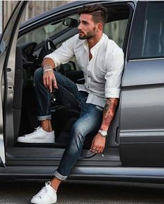 a man sitting in the back of a car with his foot on the door handle