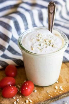 a jar filled with yogurt sitting on top of a cutting board next to tomatoes