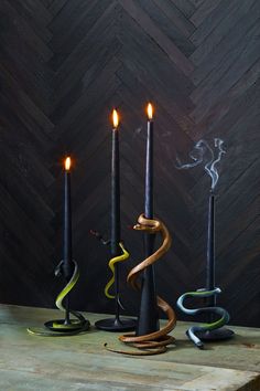 three black candles with different colored snakes on them