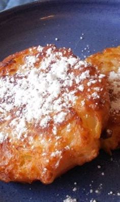 two pieces of food on a plate with sugar sprinkled on top and powdered sugar on the side