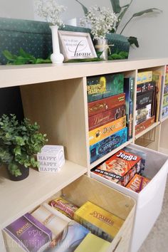 a book shelf filled with lots of books and magazines next to a potted plant