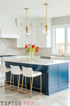 a kitchen island with three chairs and a vase filled with red flowers on top of it