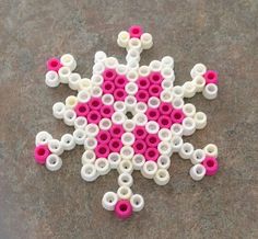 a pink and white snowflake sitting on top of a cement floor next to a pair of scissors