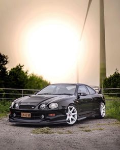 a black car parked in front of a wind turbine