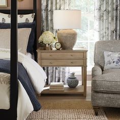 a bed room with a neatly made bed and a night stand next to a chair