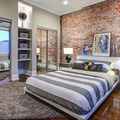 a bedroom with a brick wall and hardwood flooring, along with a large bed