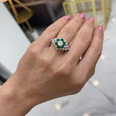 Gender: Ladies    Metal Type: 14K White & Yellow Gold    Size (US):    Width: Approximately 15.00mm tapering to 1.80mm    Diameter: 21.80mm    Weight: 5.16 Grams  This beautiful diamond cocktail ring is accented with 6 natural round emeralds with a half round shank.  Engraved with "14K".  Pre-owned in excellent condition. Might show minor signs of wear.    Prong Set in 14 Karat Yellow Gold with:    One (1) round brilliant cut natural diamond:    Measurements: 5.10mm - 5.20mm in diameter x ~3.14mm in depth.  Estimated Weight: 0.51 ct.  Color: G - H  Clarity: VS1 - VS2  Cut: Very Good  Polish: Very Good  Symmetry: Good    Prong Set in 14 Karat Yellow Gold with:    Six (6) natural, round-shaped, brilliant cut, emeralds:    Species: Natural Beryl  Variety: Natural Emerald  Measurements: 2.80mm Gia Certified Diamond Cluster Halo Ring, Cluster Diamond Emerald Ring, Cluster Emerald Ring With Diamond Center Stone, Emerald Cluster Diamond Ring With Center Stone, Cluster Emerald Ring With Diamond, Cluster Emerald Diamond Ring With Center Stone, Emerald Cluster Ring With Brilliant Cut Diamonds, Marquise Emerald Diamond Ring With Brilliant Cut, Gia Certified Cluster Ring Fine Jewelry