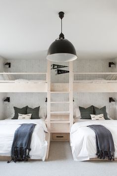 two bunk beds in a room with white walls and carpeted flooring, one has a ladder to the ceiling