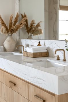 a bathroom with marble counter tops and wooden drawers, gold faucets and mirrors