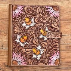 a brown leather journal with flowers and leaves on it