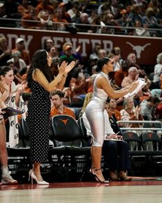 two female basketball players giving high fives to each other in front of an audience