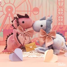 two stuffed animals that are sitting next to each other on a table with paper hearts