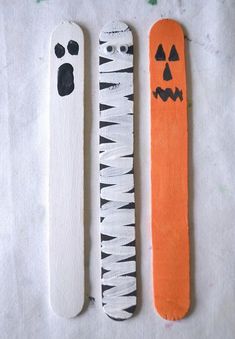 three halloween craft sticks with faces on them and one has a cat's paw